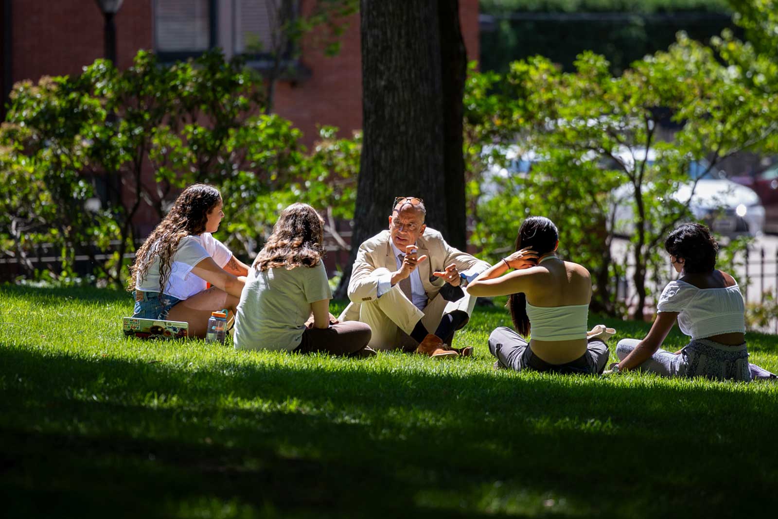 advisor and students sitting in a circle under a tree